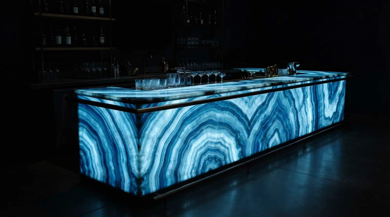 Hotel bar counter faced in translucent blue onyx glowing sapphire and ice white in a dark room